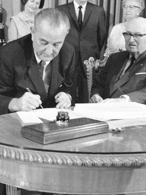 July 30, 1965 file photo, President Lyndon B. Johnson uses the last of many pens to complete the signing of the Medicare Bill into law