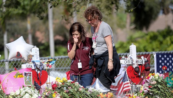 Margarita Lasalle, a bookkeeper and Joellen Berman, a guidance data specialist, look at a memorial Friday, Feb. 23, 2018 as teachers and school administrators returned to Marjory Stoneman Douglas High School for the first time since 17 victims were killed in a mass shooting.