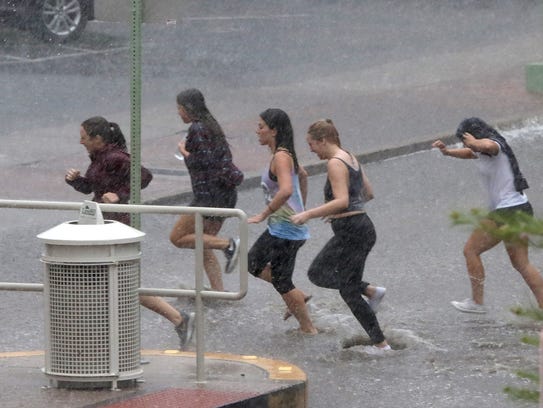 Young women get drenched as they race through the rain