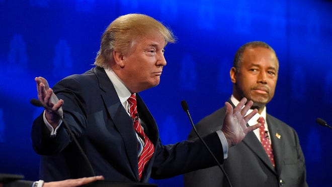 Ben Carson, right, watches as Donald Trump speaks during the CNBC Republican presidential debate at the University of Colorado, Wednesday, Oct. 28, 2015, in Boulder, Colo.