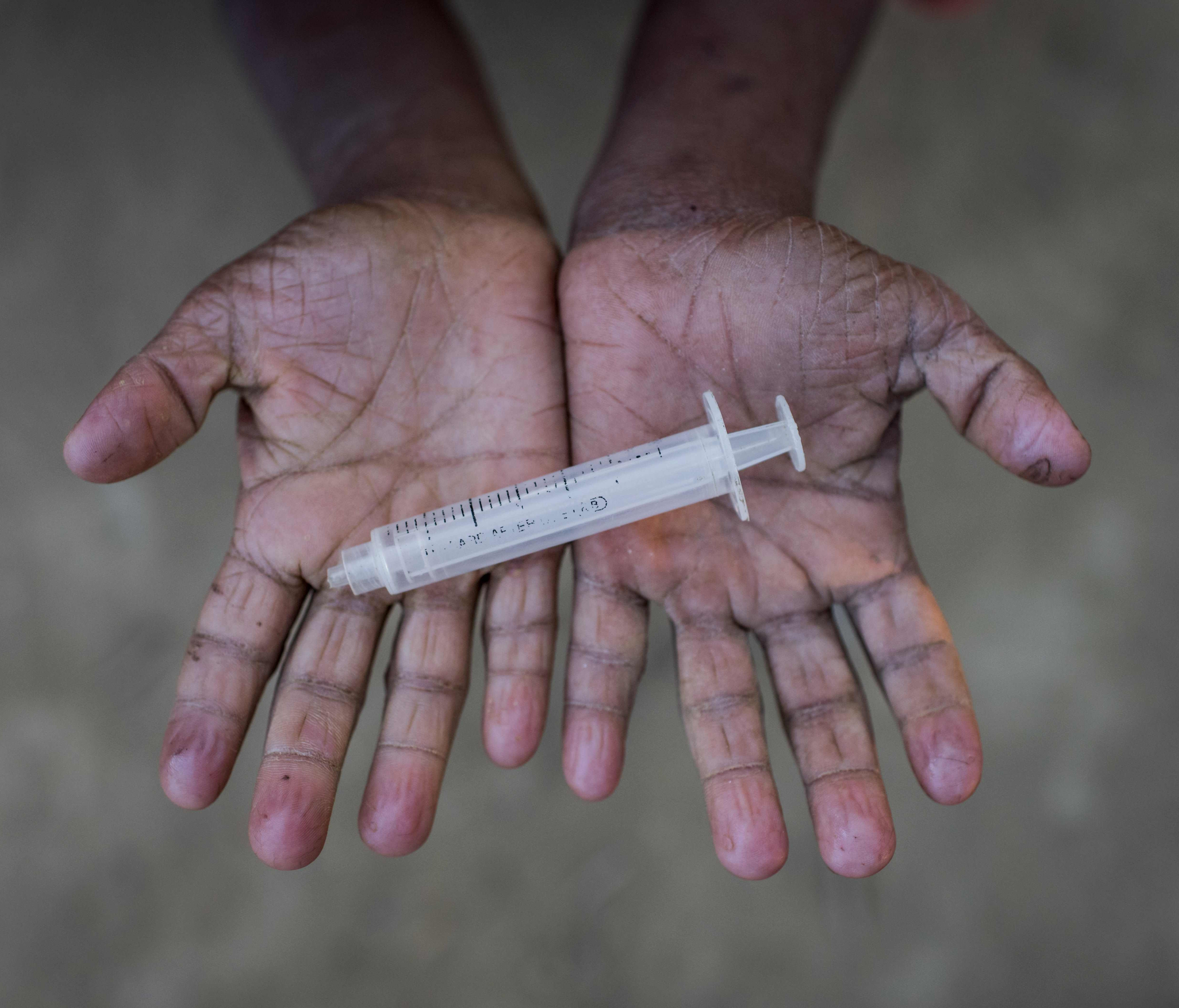 File picture - a boy holds a discarded syringe.
