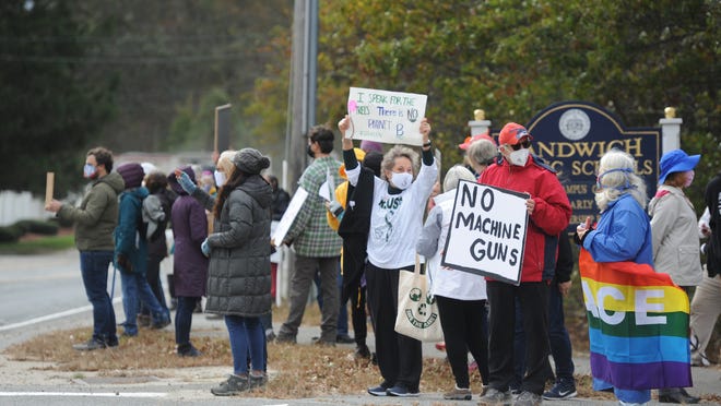 Lou Cerrone, of Sandwich, holds a sign reading "No machine guns" as he stands along Route 130 in Sandwich on Monday as part of a local protest of the proposed machine gun range on Joint Base Cape Cod.
