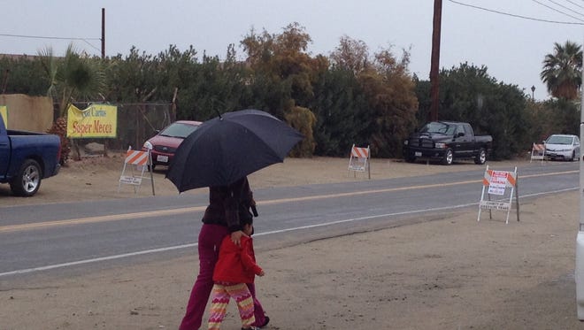 A woman and a child are seen walking in rainy conditions on Hammond Street in Mecca. (Jan. 11, 2015)