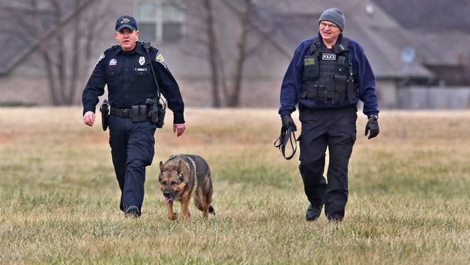 State Trooper T. Burgett, left, and Master Trooper Dennis Wade search with K9 officer Mojo as law enforcement search for a suspect after several possibly related incidents in Franklin, Friday, Jan.  2, 2015.