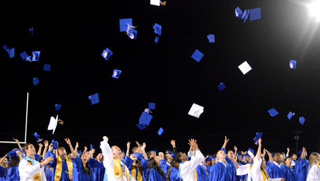 Carlsbad High seniors toss their caps up in the air to celebrate graduating on Friday.