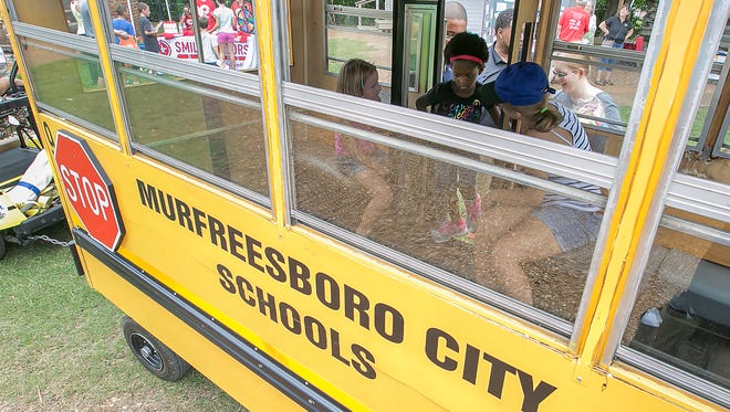 Riders get on board a pretend school bus that is pulled with a golf cart around Cannonsburgh Village at the Murfreesboro City School Back to School Bash.