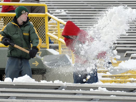 Two shovelers work inside Lambeau Field to clear snow