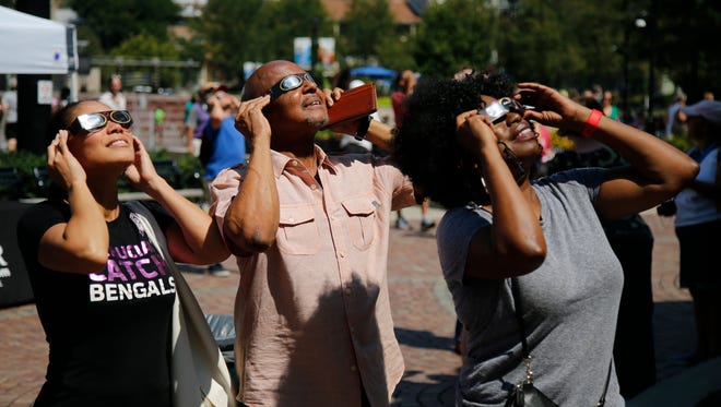 Lincoln Ware, of The Lincoln Ware Show on WDBZ 1230 The Buzz of Cincinnati, center, views the total solar eclipse at a watch party sponsored by The Enquirer, Monday, Aug. 21, 2017, at Washington Park in Cincinnati. 