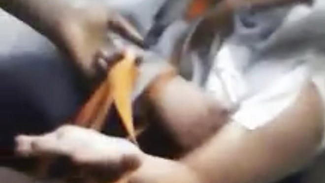 This image from a video that was broadcast live on Facebook and later posted on Vidme shows a frame in which a man, right, is assaulted in Chicago. The video shows the man with his mouth taped shut as a woman and other people cut off his shirt and hair with a knife, and someone pushes his head with his or her foot. Chicago Police Superintendent Eddie Johnson said Wednesday, Jan. 4, 2017, that the victim has mental health challenges, and he called the video "sickening." (Vidme via AP)