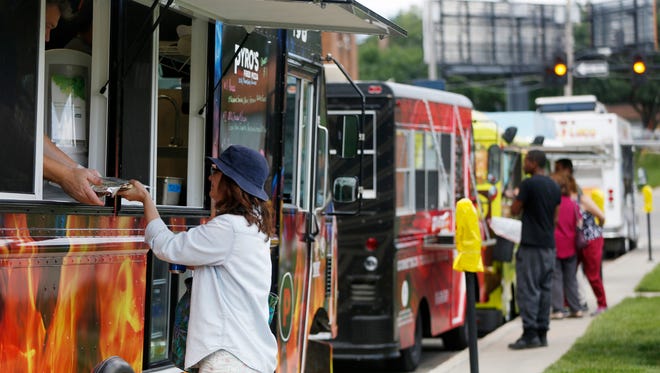 A customer purchases a meal from Pyro's Artisan Fired Pizza food truck parked on 15th street by the sculpture park in downtown Des Moines.