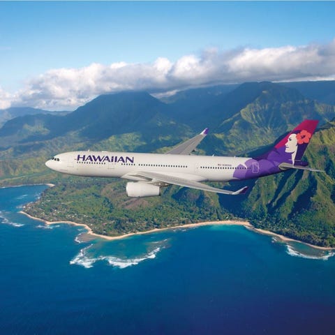 A Hawaiian Airlines plane flying over the ocean, w