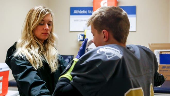 Athletic trainer Kristen Hamman evaluates a youth football player for a concussion after a junior football game. 