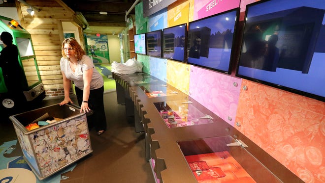 Jessica Kallas rolls a cart of separated material to the Re-Manufacturing Center where it can be processed into new products in the Retzer Nature Center's newly renovated Interactive Environmental Education Center Exhibit Space on April 3.