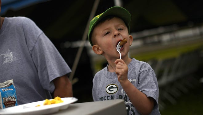 Carlson Moring, 3, of Green Bay eats a link of sausage as he dines with his family during the Brown County Breakfast on the Farm at Calf Source LLC in De Pere on June 1, 2014.
