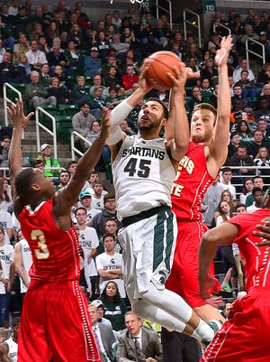 Michigan State's Denzel Valentine slashes between Ferris State defenders Josh Fleming (3) and Andrew Meacham for a basket.