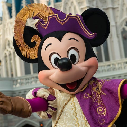 Mickey Mouse in regal attire poses in front of Cin