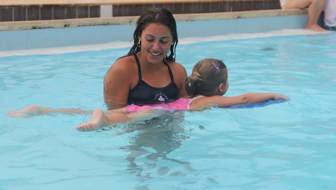 Swimming instructor showing student swimming techniques