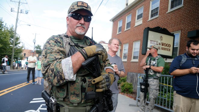 In this Aug. 12, 2017, file photo, an armed militia member stands guard at a white nationalist rally in Charlottesville, Va. Virginia Democrats, who made big gains in the swing state on Election Day, say their newfound clout has increased the odds of passing gun control measures in the coming year. (AP Photo/Steve Helber, File)