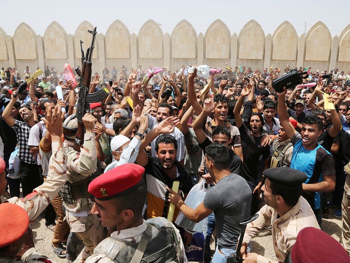 Men chant slogans against the Islamic State of Iraq and the Levant outside the main army recruiting center as they volunteer for military service in Baghdad.
