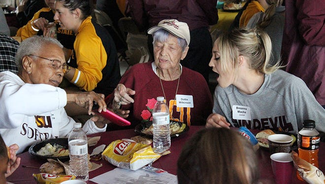 Billie Harris (left), Dottie Wilkinson (center) and ASU pitcher Breanna Macha (right) look at old photos during the ASU softball team’s lunch with former softball players. Harris is the first African-American woman inducted into the Amateur Softball Association of America Hall of Fame, while Wilkinson is not only a member of the National Softball Hall of Fame, but also the Women’s International Bowling Congress Hall of Fame. (Photo by Tyler Drake/ Cronkite News)