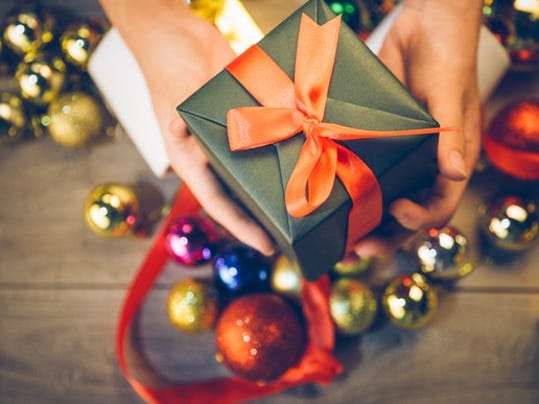 aerial-view-of-persons-hands-holding-out-a-wrapped-gift-box-over-christmas-ornaments-present-holiday_large.jpg