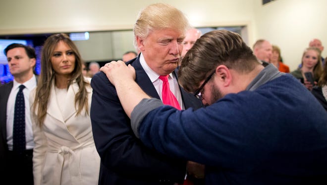 In this Jan. 31, 2016, file photo, Pastor Joshua Nink, right, prays for Republican presidential candidate Donald Trump, as wife, Melania, left, watches after a Sunday service at First Christian Church, in Council Bluffs, Iowa.
