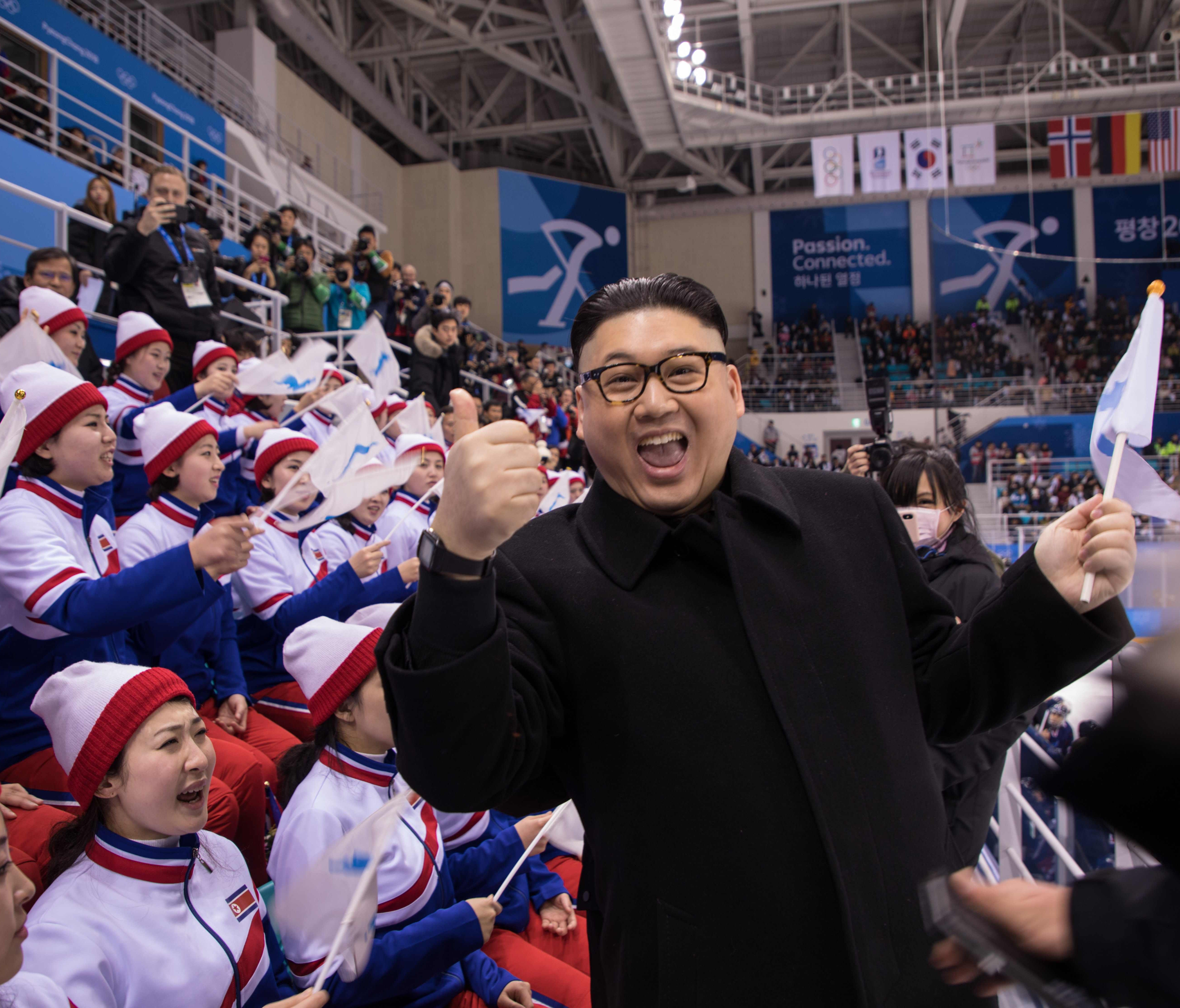 A man impersonating North Korean leader Kim Jong Un gestures as he stands before North Korean cheerleaders attending the Unified Korean ice hockey game against Japan during the Pyeongchang 2018 Winter Olympic Games at the Kwandong Hockey Centre in Ga