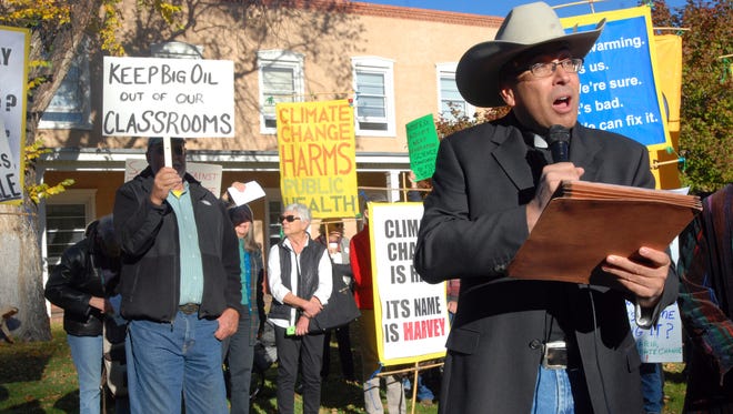 Roman Catholic Pastor Vincent Paul Chavez, right, of the Saint Therese school and parish in Albuquerque, protests proposed state science standards on behalf of the Santa Fe Archdiocese outside a public hearing in Santa Fe, N.M., Monday, Oct. 16, 2017. The proposed standards for public schools has come under intense criticism for omitting or deleting references to global warming, evolution and the age of the Earth. Comments at the hearing overwhelmingly sided against state revisions to a set of standards developed by a consortium of states and the National Academy of Sciences.