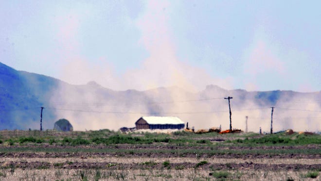Seen through heat waves, a dust storm blows behind a farm west of Lovelock in May.