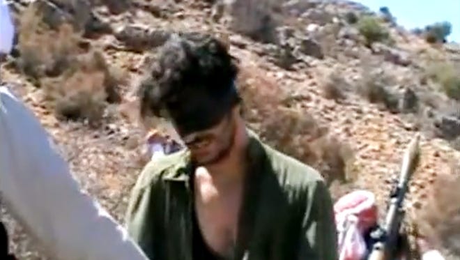 In this image taken from undated video posted to YouTube, American freelance journalist Austin Tice, a former U.S. Marine who had been reporting for U.S.  news organizations in Syria until his disappearance in August 2012, prays in Arabic and English while blindfolded in the presence of gunmen. The Associated Press could not independently confirm the origin or the content of the clip, but the Tice family released a statement to several media outlets confirming it was their son in the video. Although the video footage shows a group of captors dressed and behaving like Islamist extremists, the clip lacks the customary form of jihadist videos.