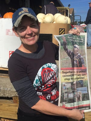 Jane Kleeb, Bold Nebraska director and Bold Alliance president, holds up an advertisement for the original June sacred Ponca corn planting at the follow-up harvest event on Oct. 14, 2016, in Stuarts Draft, Va.