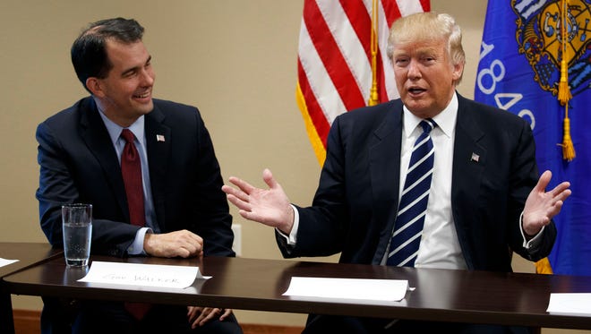 Wisconsin Gov. Scott Walker listens as Republican presidential candidate Donald Trump speaks during a meeting with small business leaders Tuesday in Altoona.