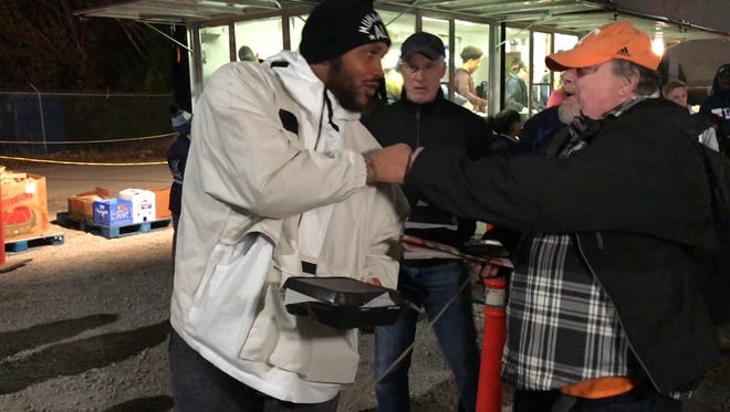 Titans defensive lineman Jurrell Casey, left, hands out a Thanksgiving meal during the team's community outreach event Tuesday, Nov. 20, 2018, in which players, coaches and members of the organization helped feed the homeless under the Jefferson Street Bridge.