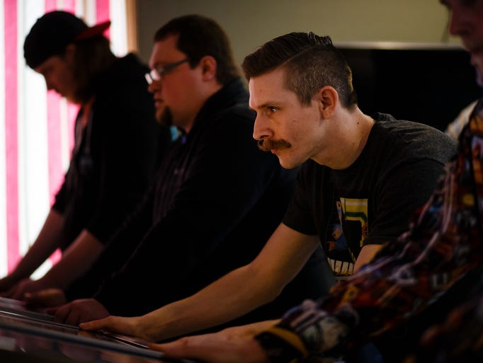 Troy Evans, 35 of Fairbank, focuses on a game of pinball