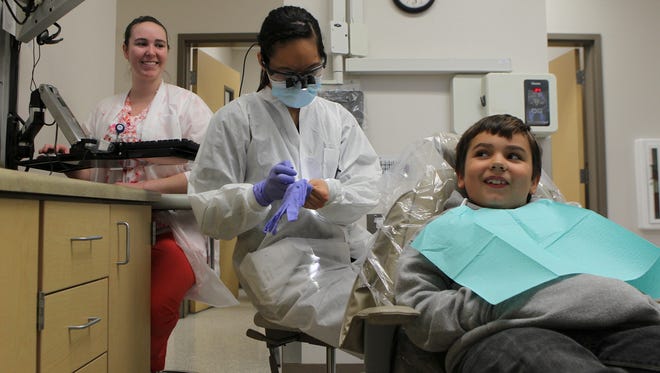 Michael Rulison, 10, right, talks with Bonnie Le, a Western University intern, center, and Rikki Barnes, left, dental assistant with Shasta Community Health Dental Center, on Jan. 18 during an exam.
