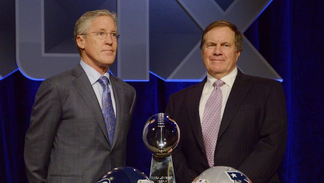 Seattle Seahawks head coach Pete Carroll (left) and New England Patriots head coach Bill Belichick (right) pose for a photo with the Vince Lombardi Trophy and team helmets during a press conference for Super Bowl XLIX at Phoenix Convention Center.