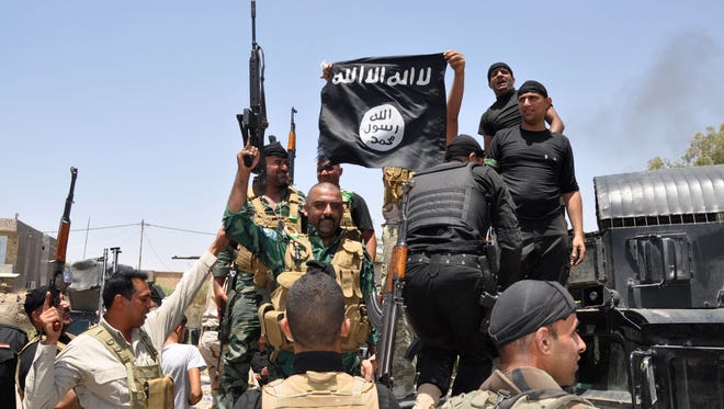 Iraqi security forces display a flag of the Islamic State in Iraq and Syria on June 28  that was captured during an operation.