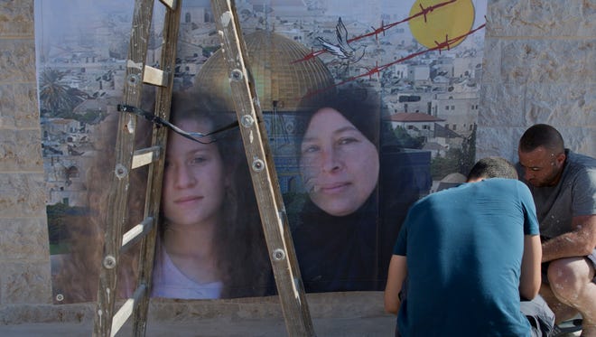 Palestinians hang a poster showing Nariman Tamimi, right and her daughter Ahed, during preparations for their upcoming release from an Israeli prison after serving an eight month sentence.