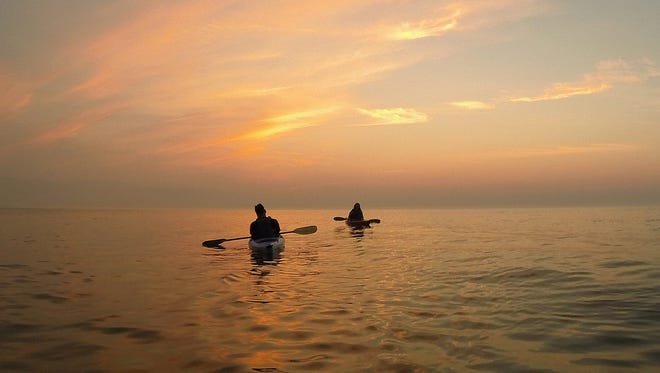 Kayakers paddle on Lake Michigan at sunrise in August 2015 near Cedar Grove.