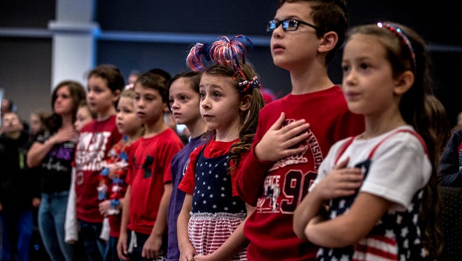 Students stand for the singing of the National Anthem Friday at Granville Christian Academy's Veteran's Day service. 