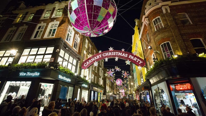 Shoppers walk beneath the Christmas lights on Carnaby Street in central London on Dec. 20, 2015, on the final shopping Sunday before Christmas.