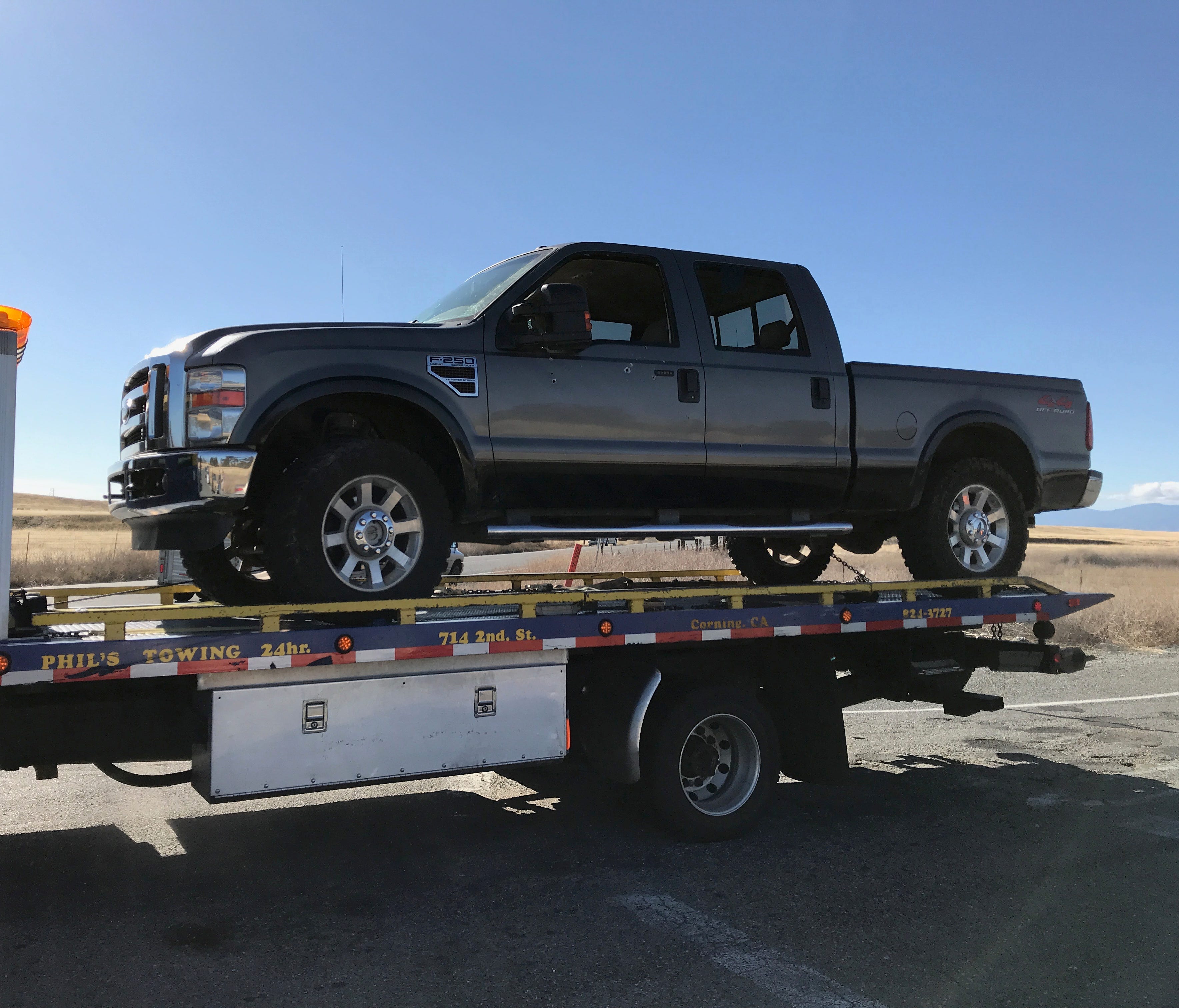 A tow truck removes a pickup with bullet holes in its side from Rancho Tehama on Tuesday. A shooter killed at least four people in a mass shooting in the Tehama County subdivision.