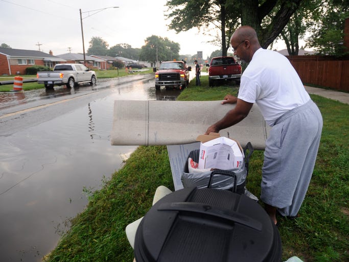 Man carries damaged household items to curbside.