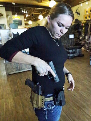 Alexandra Wilson, marketing director and firearms instructor at Sportsman's Elite indoor shooting range and pro shop at 4520 Doniphan, shows two varieties of handgun holsters.