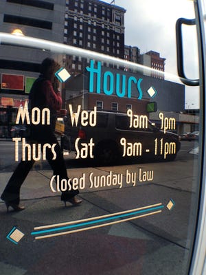 A sign on a liquor store reads "Closed Sunday by Law."