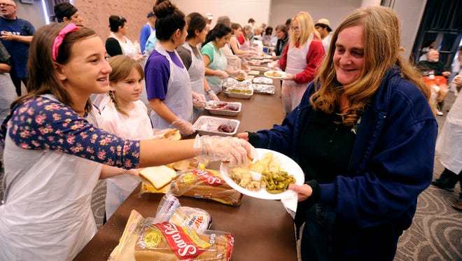 Volunteer Ella Munshower (left), 11, hands out bread to diners during the Veterans Service Office's Operation Thanksgiving meal on Thursday, Nov. 24, 2016, at the Abilene Civic Center. 