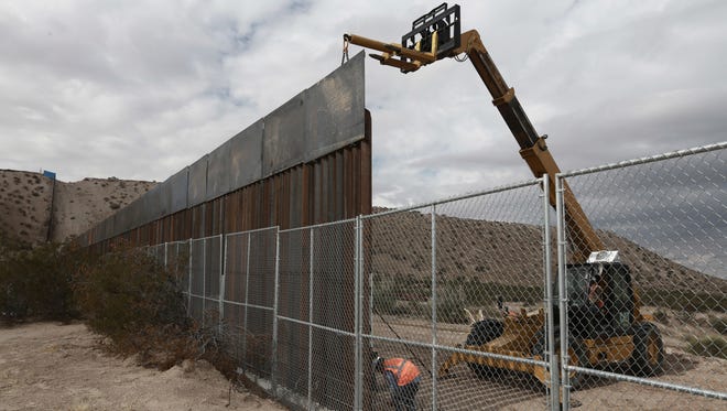 In this Nov. 10, 2016 photo, workers raise a taller fence along the Mexico-US border between the towns of Anapra, Mexico and Sunland Park, New Mexico, where for almost two decades a Mass has been celebrated on Day of the Dead to remember migrants who have died trying to cross the fence. President-elect Donald Trump has threatened to force Mexico to pay for a wall along the nearly 2,000-mile (3,145-kilometer) border.