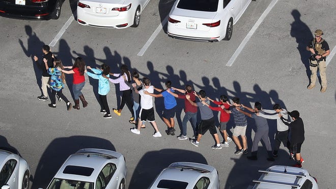 People are brought out of the Marjory Stoneman Douglas High School after a shooting at the school that reportedly killed and injured multiple people on February 14, 2018 in Parkland, FL.