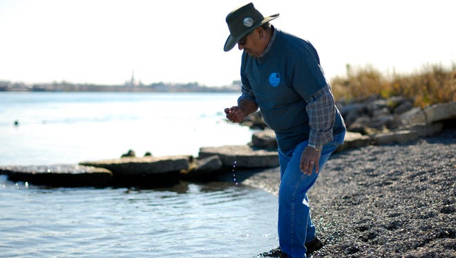 Steward with the Friends of the St. Clair River, Marcus Middleton, picks up and checks out a stone Monday, Nov. 16, along the Blue Water River Walk in Port Huron.