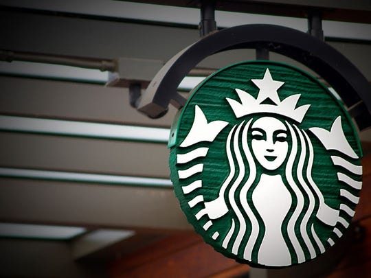 Starbucks mermaid logo on circular sign hanging from ceiling.